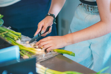 Cold meats and sausages arranged on plates, and two women whose hands can be seen arranging and cutting onions