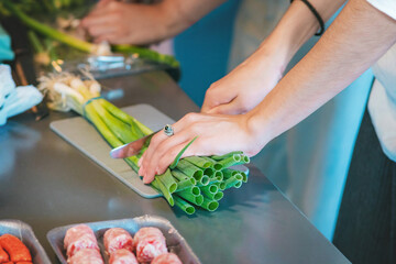 Cold meats and sausages arranged on plates, and two women whose hands can be seen arranging and cutting onions