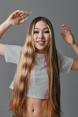 Young woman smiling with long straight hair wearing casual white t shirt posing with raised hands...