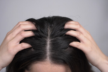 Fototapeta premium A close-up view of a person using both hands to massage their scalp or examine their hair part.