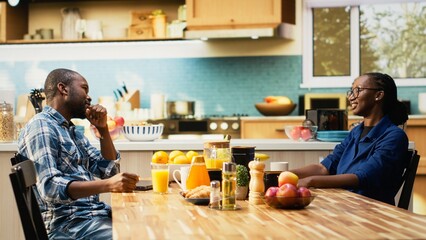 African american man working too hard and woman asking for a break, showing him the timeout sign and closing his laptop. Workaholic boyfriend ignoring his girlfriend during breakfast.