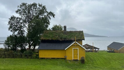 Obraz premium Traditional yellow wooden house with grass roof by a fjord in Norway.