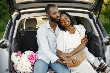 Lovely african couple sitting in a car trunk