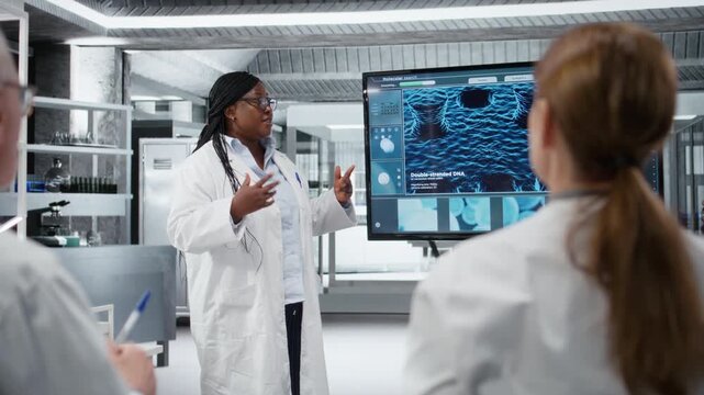 Medical school professor taking questions from students during seminar on advanced cell biology. African american academic expert teaching using digital screen in laboratory, camera A