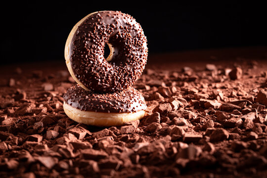 Sweet chocolate donuts on cocoa powder and chocolate bars.
