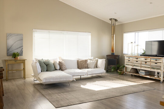 White low-profile sectional sofa is anchoring living room, on rug with striped light and pillows