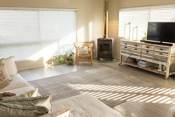 Light-gray rug is receiving striped sunlight in coastal living room with sectional and stove