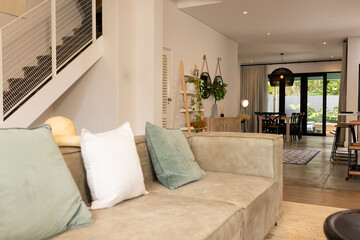 Beige suede sectional sofa occupying center foreground, featuring three pillows and straw sun hat