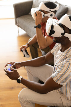 Two men are wearing white VR headsets and holding controllers in home living room