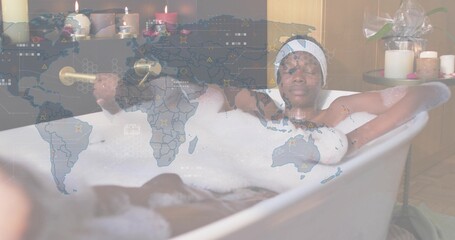 Reclining woman wearing white headband soaking in clawfoot bathtub at home, bubbles and map overlay