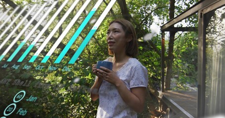 Standing midadult-Chinese woman in top holding ceramic mug gazing at trees on deck with AR chart