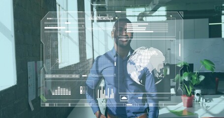 Standing man wearing blue shirt and dark trousers viewing holographic UI in office
