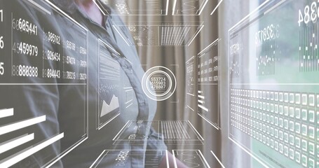 Standing mature woman wearing dark blazer facing holographic interfaces at office, with data panels