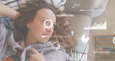 Reclining adult woman wrapped in knit shawl on sofa in living room, with HUD and pillows