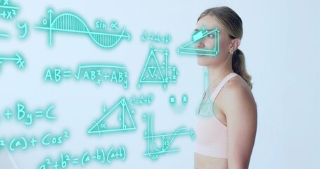 Observing woman in pink athletic crop top studying holographic math diagrams in studio, copy space
