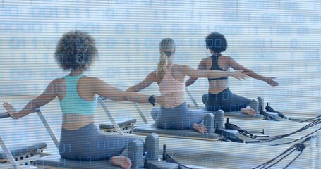 Doing three women wearing sportswear practicing pilates on reformers in studio with straps