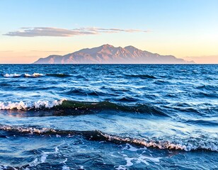 A scenic coastal view showcasing a vast expanse of ocean with gentle waves, and a mountainous island silhouette in the distance
