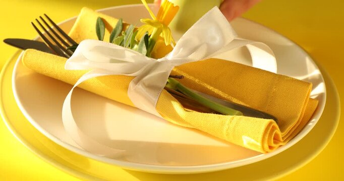 Easter celebration. Woman setting table for festive dinner on yellow background, closeup