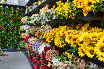 Obraz premium Colorful display of a wide variety of artificial floral arrangements on the shelves.