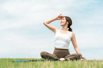 A woman meditating, doing yoga, stretching, and pilates in the grassland (healthcare and diet)