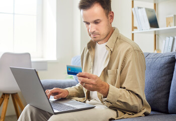 Man uses laptop, credit card for online payment. He verifies banking details and enters checkout...