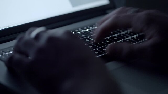 Hands Typing on Computer Keyboard in Dark Workspace
