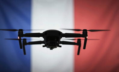 A quadcopter drone is silhouetted against the iconic blue, white, and red French national flag.