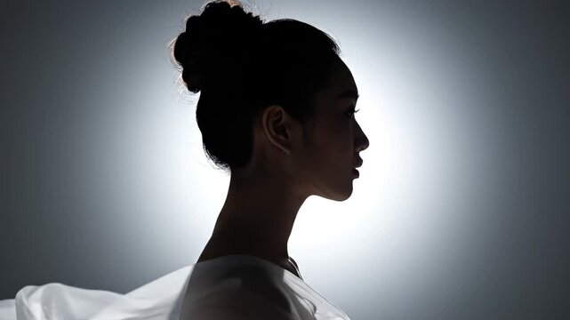 Profile of woman with hair in bun and sheer fabric