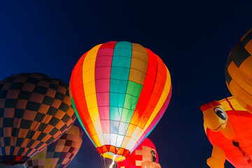 colorful hot air balloons glowing against dark night sky