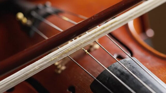 Macro close-up of violin bow moving across strings playing classical music