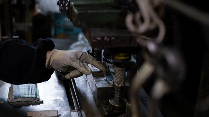 Worker positioning sheet metal parts on press machine during manufacturing process in small factory