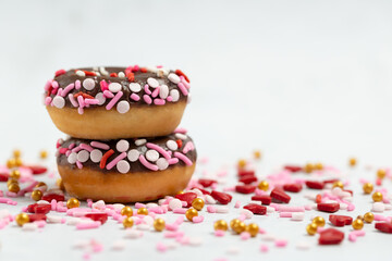 Chocolate Frosted Donuts with Pink Sprinkles on White Background