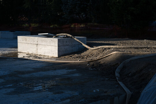 Underground stormwater tank with camlock industrial heavy duty dewatering hose for pumping out rainwater running across stie to access point, new construction job site
