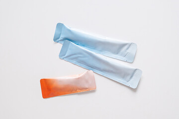 Two blue and one orange sealed packet of powdered medicine.
