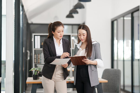 Asian businesswoman sitting at work using laptop talking and consulting in office	