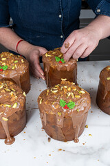 The confectioner is finishing the pennetone with a chocolate and pistachio topping and marzipan_vertical.