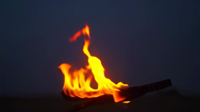 A fiery torch against a dark, blueish-grey backdrop with a soft gradient