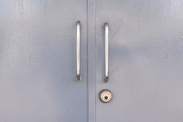 grey metal double door with two stainless steel grab handles and keyhole