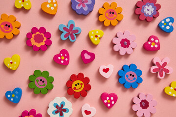 A vibrant flat lay of colourful beads flowers and hearts shape with cheerful patterns and smiley faces icon on soft pink background. For Valentine's day and birthday greeting cards