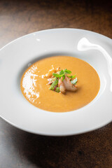 Gourmet seafood bisque soup with grilled shrimp and microgreens in white bowl 