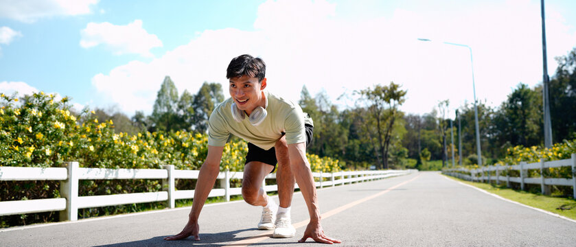 Smiling active man sitting in start position, jogging running and walking doing fitness in the park
