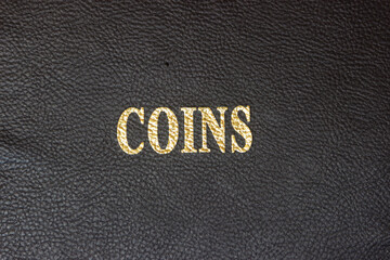 Coins with gold lettering on a black leather base