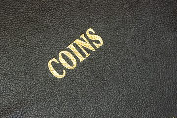 Coins with gold lettering on a black leather base