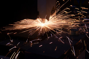 Cutting metal with a laser machine, the laser head cuts the metal, sparks fly when it comes into contact with the surface