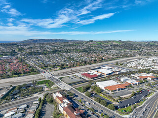 Fototapeta premium Aerial view over San Juan Capistrano, California, featuring the historic mission, library, sports courts, and an Amtrak train pulling into the downtown station. High quality 4k footage