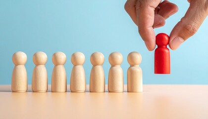 Hand lifting red figurine among wooden figures