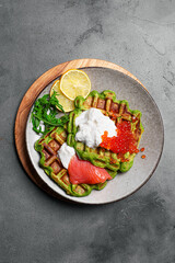 Healthy low carb breakfast with green avocado waffles, salmon, red caviar, soft cheese