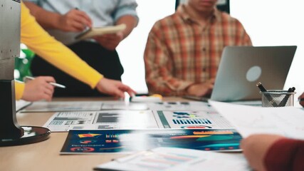 A diverse team engages in a business meeting, analyzing data on laptops and charts, fostering collaboration and strategic planning in a modern office setting. SACTR - Powered by Adobe