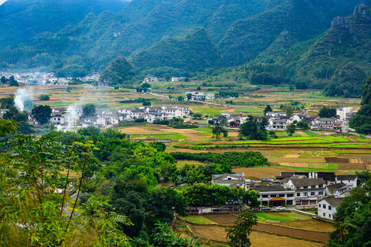 A traditional Buyi village nestled beneath the karst peaks of Wanfenglin, with stone dwellings and terraced fields blending into the majestic Guizhou landscape.
