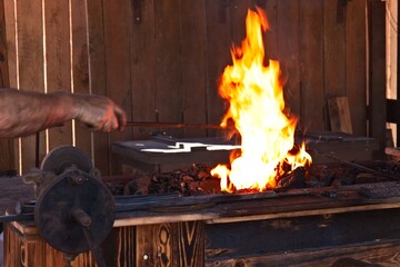 A blacksmith working an iron rod in a fire.